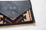Textured black Swag and Tassel clutch flap, metal corner, unique geometric rug pattern.