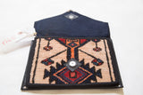 Magnetic snap on a geometric rug fragment clutch, featuring beige, navy, and red pattern.