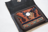 Earthy red, navy, green geometric pattern on a hand-knotted rug fragment with magnetic snap.