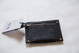 Black textured leather coin purse with silver metal zipper and attached tag.