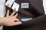 Handmade clutch interior, featuring brown leather zipper pocket and Swag and Tassel label.