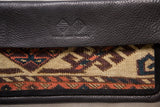 Textured leather with Swag and Tassel logo, geometric tribal rug fragment.