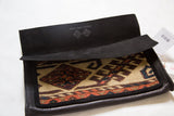 Black suede interior flap with an embossed logo and geometric vintage rug fragment.