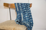 Hand-dyed indigo textile showing intricate striped and crescent patterns.