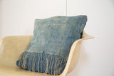 Handmade African Indigo pillow showing faded blue hand-woven textile and fringed edge.