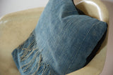 Sun-faded blue African Indigo pillow showing textured fabric and frayed edge.