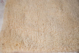 Close-up of the plush, hand-woven cream Moroccan shag bath mat pile.