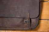 Vintage leather messenger bag closure with rich brown patina, buckle, and strap.
