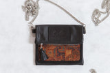 Antique Kurdish rug fragment bag with black leather, a geometric panel in warm tones, and a silver chain strap.