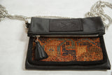 Embossed black leather flap, silver zipper, and tassel on a colorful Kurdish rug handbag.