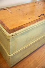 Industrial factory cart's corner, showing chipped light green paint and wood patina.