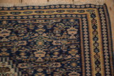 Intricate navy and camel borders and ivory fringe on the corner of an antique Persian Senneh Kilim.
