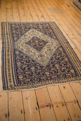Angled view of the antique Senneh kilim's stepped ivory medallion and navy field.