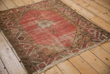 Angled view of vintage Malayer rug's faded blush field, diamond medallion, and geometric borders.