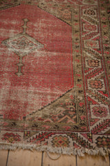 Vintage Malayer rug's blush pink field and patterned border with visible wear and tattered fringe.