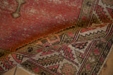 Curled vintage Malayer rug reveals geometric border in blush, ivory, and charcoal brown.