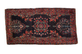 Fine Sarouk vintage Persian rug with scrolling floral vines on a dark indigo blue field with a raspberry red border.