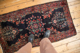 A vintage Sarouk runner seen from above, with rich raspberry red floral designs on a dark indigo blue field.