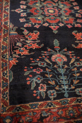 Close-up of fine Sarouk rug's scrolling floral vines in raspberry red and celadon green.