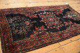 Angled view of a vintage Sarouk runner showcasing its scrolling floral vines on a dark indigo field.