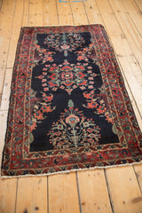 Angled view of a vintage Sarouk runner showing the triple floral medallions on its deep indigo ground.