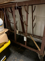 Industrial rolling storage rack with a brown metal frame and rows of welded hooks.
