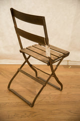 Curved metal base and legs of vintage French cafe chair, showing aged patina.
