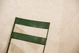 Vintage French cafe chair's green metal back with age-softened patina and string.