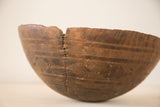 Primitive African bowl showing hand-carved dark wood with a distinct zig-zag metal repair.