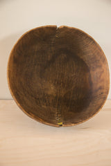 Bottom edge of the vintage wooden African bowl with visible yellow repair stitching.