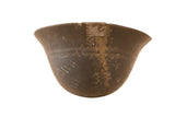 Dark, primitive African wooden bowl, hand-carved with patterns, visible cracks, and metal repair.
