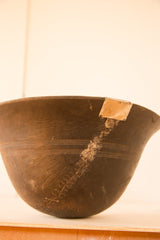 Vintage African wooden bowl with prominent staple repair and carved primitive patterns.