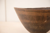 Dark hand-carved wood of vintage African bowl showing horizontal lines and rustic top edge.
