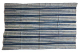 Collectible hand woven African indigo textile throw featuring varied blue and cream stripes.