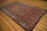 Angled view of an antique Persian Bijar rug, showing the allover Herati design and elaborate multi-banded border.