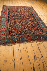 Angled view of the antique Bijar rug's dense Herati field and contrasting sky blue border.