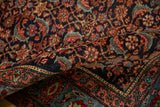 Folded corner of an antique Bijar rug revealing its dense pile, Herati motif, and ivory inner border.