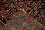 Folded corner of an antique Persian Bijar rug reveals its dense pile and detailed hand-knotted foundation.