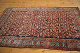 Side profile of the entire antique Bijar rug, showcasing its dense Herati field and elaborate border.