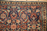 The finely woven corner of a collector Tabriz rug showing a classic Herati pattern in navy and teal.