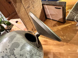 Angled close-up of the vintage moon globe piggy bank's coin slot and grey crater texture.