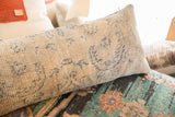 Close-up view of the beige woven texture and blue geometric details on a rug fragment pillow.