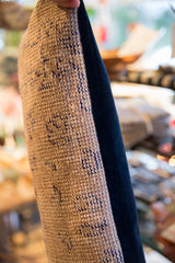 Textured beige vintage rug fragment with blue patterns and rich navy velvet backing.