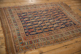 Angled view of an antique Afshar rug with a repeating boteh field and striped kilim finish.