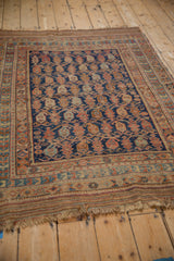 Angled view of an antique Afshar rug, highlighting its original kilim end and boteh pattern.