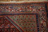 Corner of a vintage Sarouk rug with an oxidized copper spandrel and secured woven end.