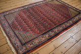 Vintage Arak Sarouk rug shown at an angle, highlighting its brick red field and celadon green spandrels.