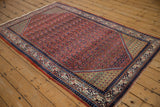 Angled view of a vintage Arak Sarouk rug highlighting its brick red field and copper green spandrels.