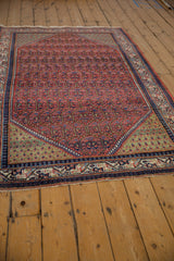 Angled view of a vintage Arak Sarouk rug showing its red allover pattern and green spandrels.