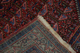 Folded corner of a vintage Arak Sarouk rug reveals the hand-knotted foundation and weave.